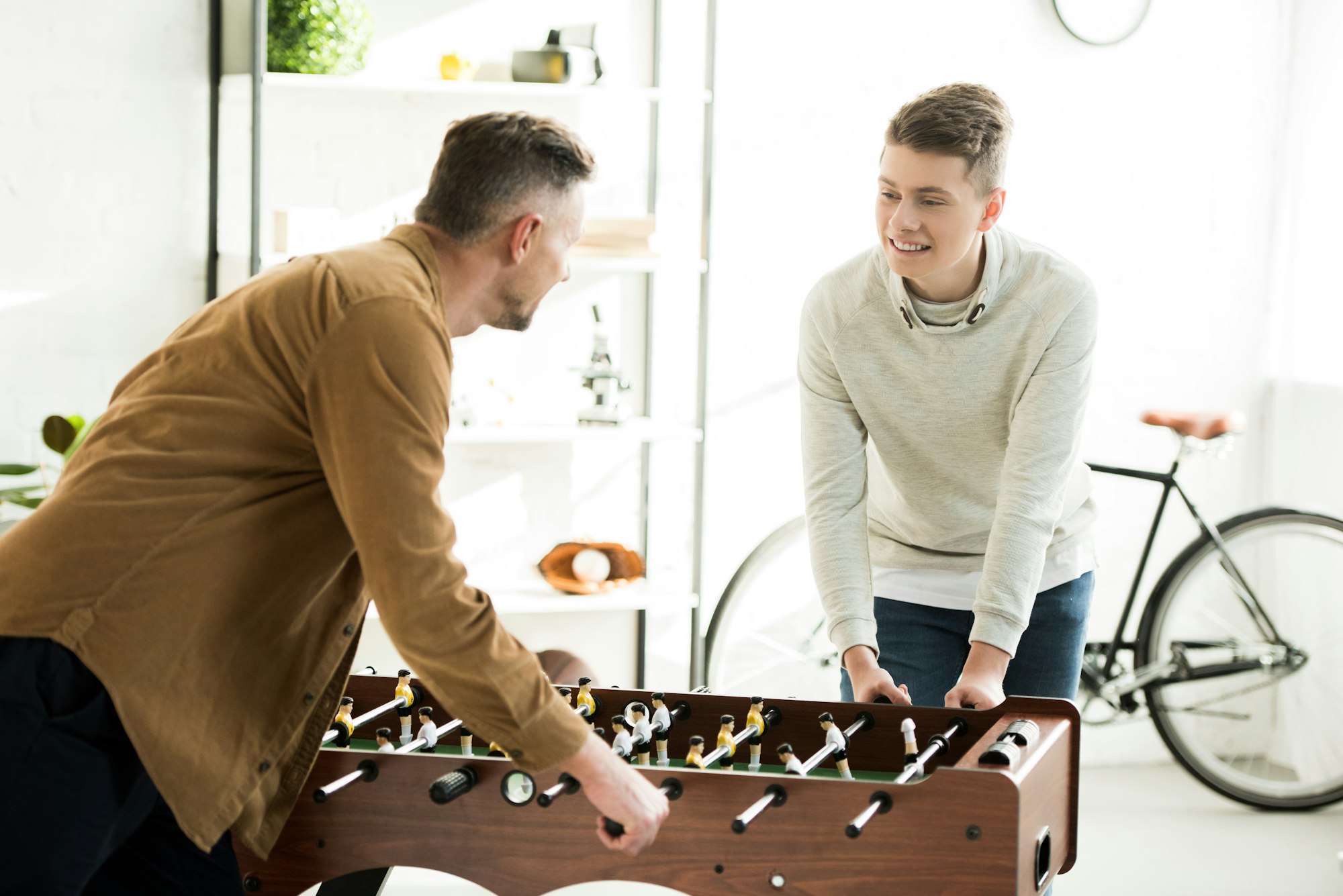 father and teen son playing table football together at home