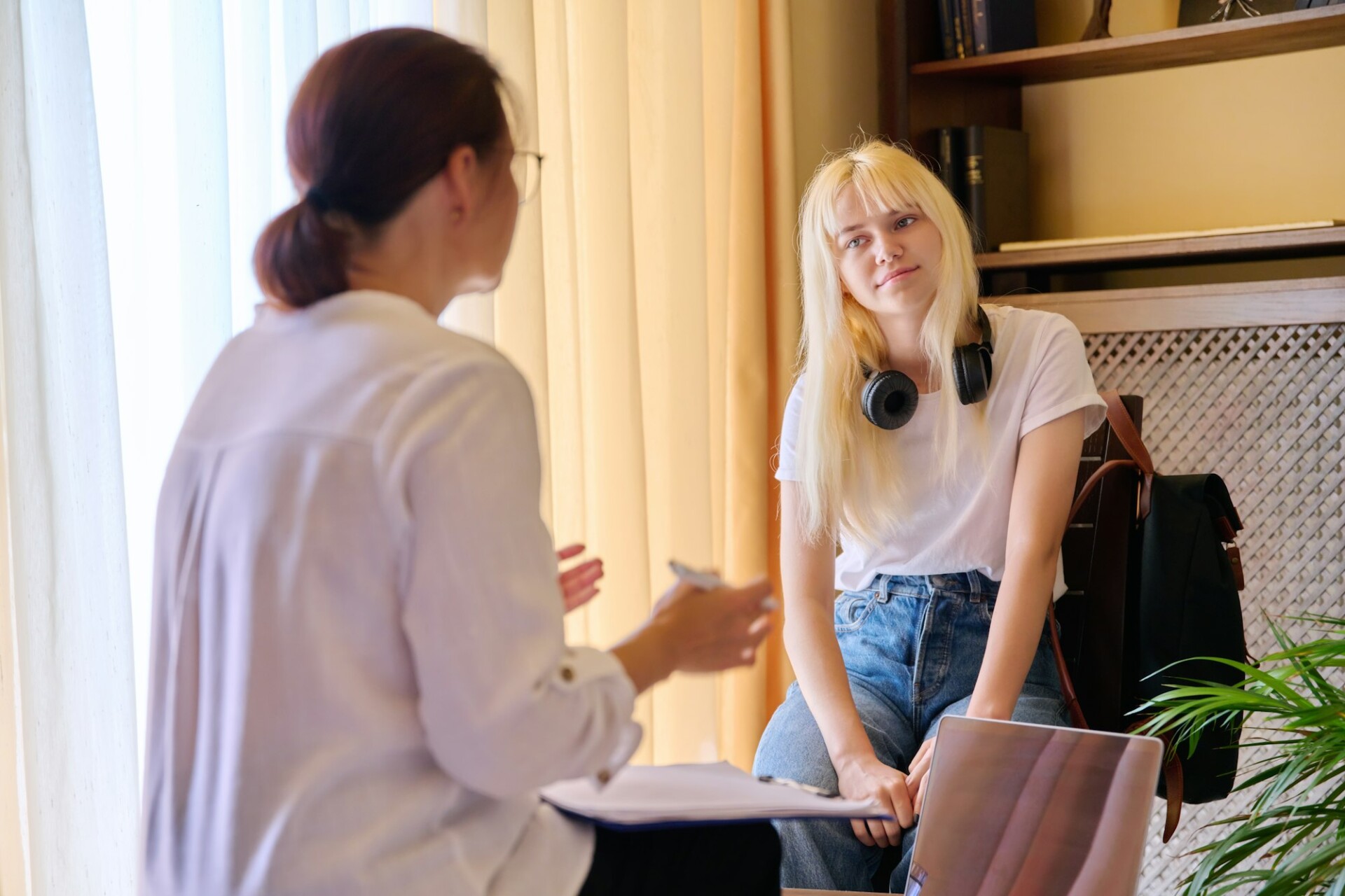 Counselor, social worker, psychologist advising a female teenager in the office